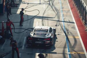 Speed Coupe parked at modern race track pit lane with mechanics working on the car during high speed racing event photo