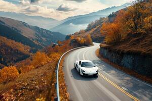 Speed Compact sports car speeding along winding mountain road with autumn foliage and distant mountain peaks photo