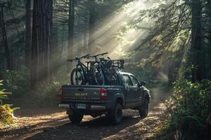 Utility Compact truck loaded with mountain bikes parked at trailhead in forested arewith sunlight filtering through the trees photo
