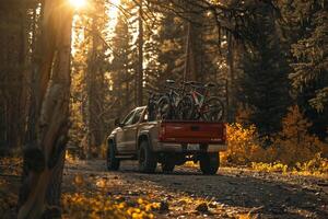 Utility Compact truck loaded with mountain bikes parked at trailhead in forested arewith sunlight filtering through the trees photo