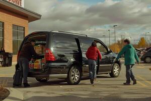 Versatility Family minivan parked at suburban shopping mall with parents loading groceries into the trunk and children getting into the back seats Background photo