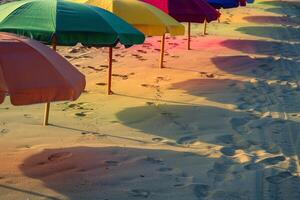 Calmness at the beach with row of beach umbrellas casting colorful shadows on the sand photo