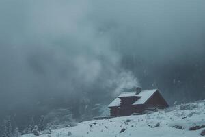 Snowstorm enveloping mountain cabin with smoke rising from the chimney set against snowy background photo