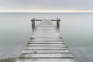 Wooden Pier Stretching into Calm Ocean Waters in Nature Background photo