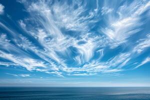 Nature Background of Wispy Cirrus Clouds in a Blue Sky Over the Ocean photo