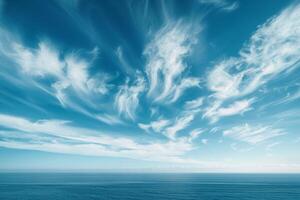 Nature Background of Wispy Cirrus Clouds in a Blue Sky Over the Ocean photo