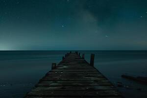 Vintage Beach Pier Extending into Calm Waters at Night with Starry Sky Background photo