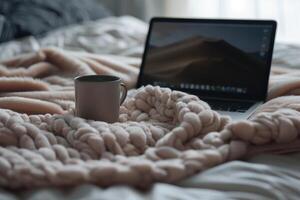 Cozy Laptop Mockup on a  Bed with a Warm Blanket and Coffee for a Relaxed Workspace Setup photo