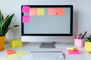 Computer mockup with sticky notes on a white desk demonstrating an organized and  workspace background photo