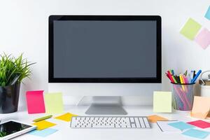 Computer mockup on a  white desk with sticky notes around ideal for office setup and  work background photo