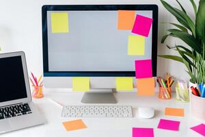 Computer mockup on a white desk with sticky notes suitable for project organization and  work background photo