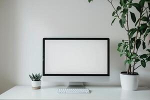 Computer mockup with plant on a white desk in a  workspace photo
