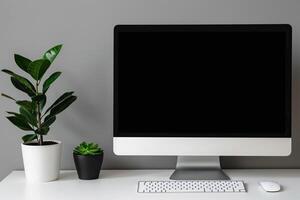 Computer mockup on a white desk with a plant in a stylish setup photo
