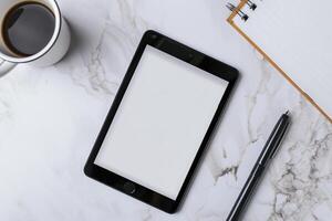 Tablet on Desk with Pen and Notepad on Wooden Surface photo