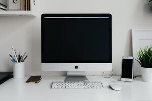 White Desk Computer Mockup Surrounded by Writing Materials photo