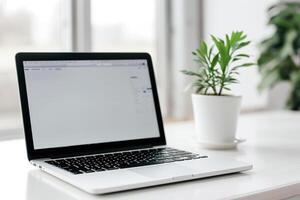 Laptop Mockup on White Desk with Open Notebook and Writing Materials photo