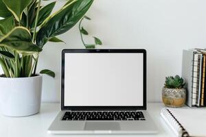 Laptop Mockup on White Desk with Open Notebook and  Writing Materials photo