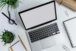 Writing and Laptop Mockup Setup on White Desk with Open Notebook Background photo