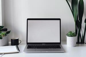 Work Setup with Laptop Mockup and Open Notebook on White Desk Background photo