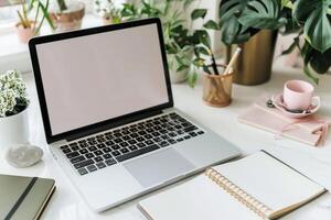 Writing and Laptop Mockup Setup with Open Notebook on White Desk Background photo