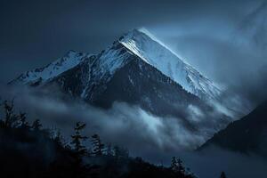 Snow Capped Mountain Peak at Dawn with Mist Swirling Around in a Breathtaking Winter Landscape photo
