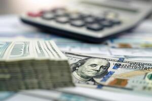 Stack of Hundred Dollar Bills with Calculator and Financial Report photo