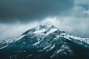 Snow Capped Mountain Peak at Dawn with Mist Swirling Around in a Majestic Winter photo