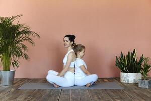 Smiling mother and daughter practicing yoga together photo