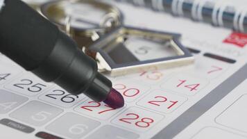 House keys with a keychain in the form of a house and selected date on the calendar. Marked day in a wall calendar. video