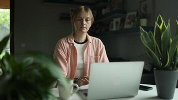 Young Caucasian female in stylish casual clothes sit has training online meeting on laptop computer indoors slow motion video
