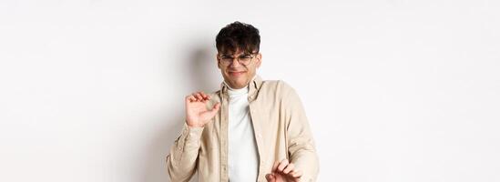 Disgusted guy grimacing and jumping away from something nasty, stare with aversion and dislike, rejecting bad offer, standing on white background photo