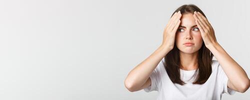 Close-up of embarrassed and shocked young beautiful woman facepalm and looking awkward, white background photo