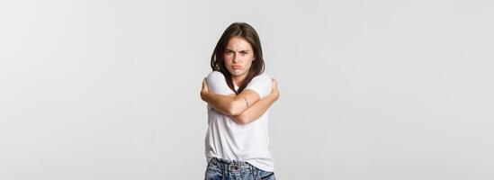 Offended sulking girl looking defensive and hugging herself photo