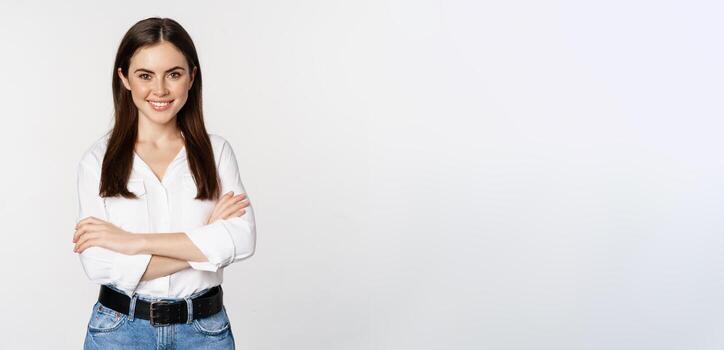sonriente joven mujer de negocios, hembra empresario en blanco camisa, cruzar brazos en cofre me gusta profesional, en pie terminado estudio antecedentes foto