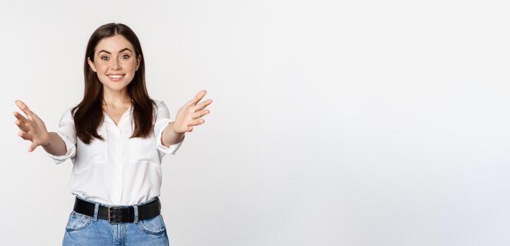 entusiasta riendo mujer, sonriente y extensión fuera brazos adelante, Bienvenido tú, saludo, en pie terminado blanco antecedentes foto