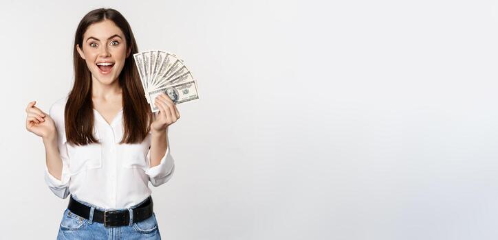 entusiasta mujer demostración dinero, efectivo y sonriente, tiene préstamo, micro crédito, en pie Encantado en contra blanco antecedentes foto