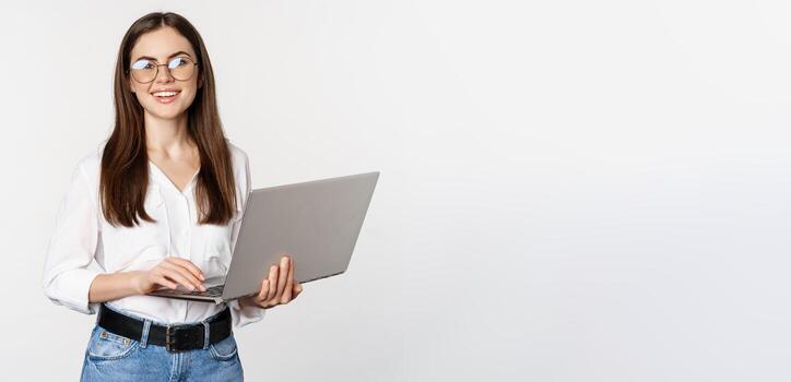 retrato de joven oficina mujer, empresario responder clientela en computadora portátil, trabajando con computadora con contento rostro, en pie terminado blanco antecedentes foto