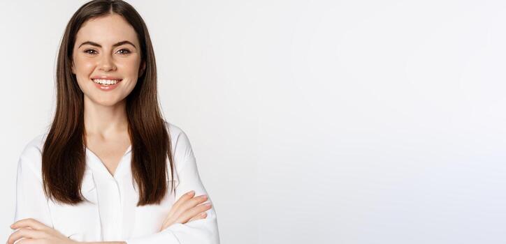 cerca arriba de confidente corporativo mujer, profesional empresario sonriente, cruzar brazos en cofre y sonriente entusiasta, en pie terminado blanco antecedentes foto