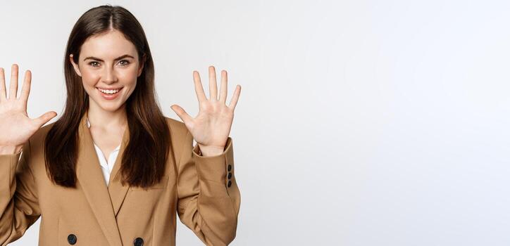 retrato de corporativo mujer, vendedora demostración número diez dedos y sonriente, en pie en traje terminado blanco antecedentes foto