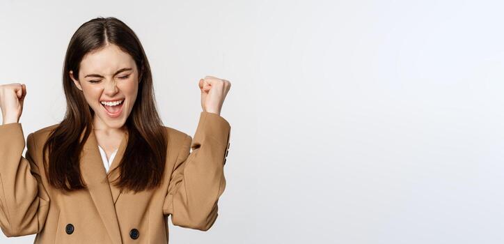 entusiasta niña gritando y alegría, mirando a cámara, victorioso, celebrando victoria y triunfando, en pie terminado blanco antecedentes foto