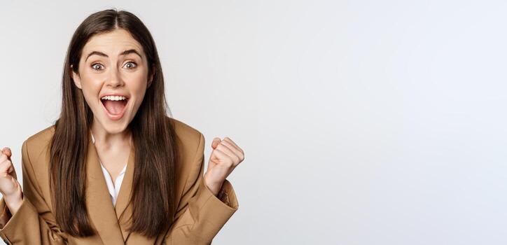 entusiasta niña gritando y alegría, mirando a cámara, victorioso, celebrando victoria y triunfando, en pie terminado blanco antecedentes foto