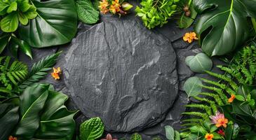 Round Black Slate Stone Surrounded by Tropical Greenery and Flowers photo