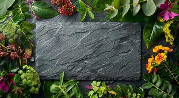 Round Black Slate Stone Surrounded by Tropical Greenery and Flowers photo