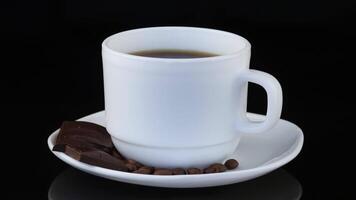 Coffee in a cup and pieces of chocolate on a white background video