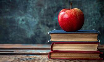 A Red Apple Resting Atop Stacked Books On Wooden Table photo