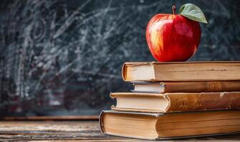 Stack of Books With Red Apple in Front of Chalkboard photo
