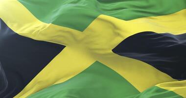 Flag of Jamaica waving at wind with blue sky in slow, loop video
