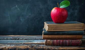 A Red Apple Resting Atop Stacked Books On Wooden Table photo