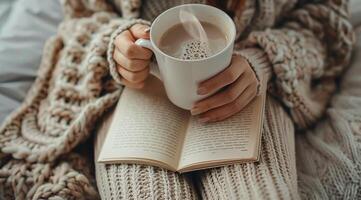 Woman Reading a Book and Enjoying a Hot Beverage on a Cozy Day photo