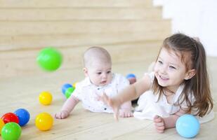 Baby boy and his sister playing with balls. Colorful toys for kids. Kids in play room photo